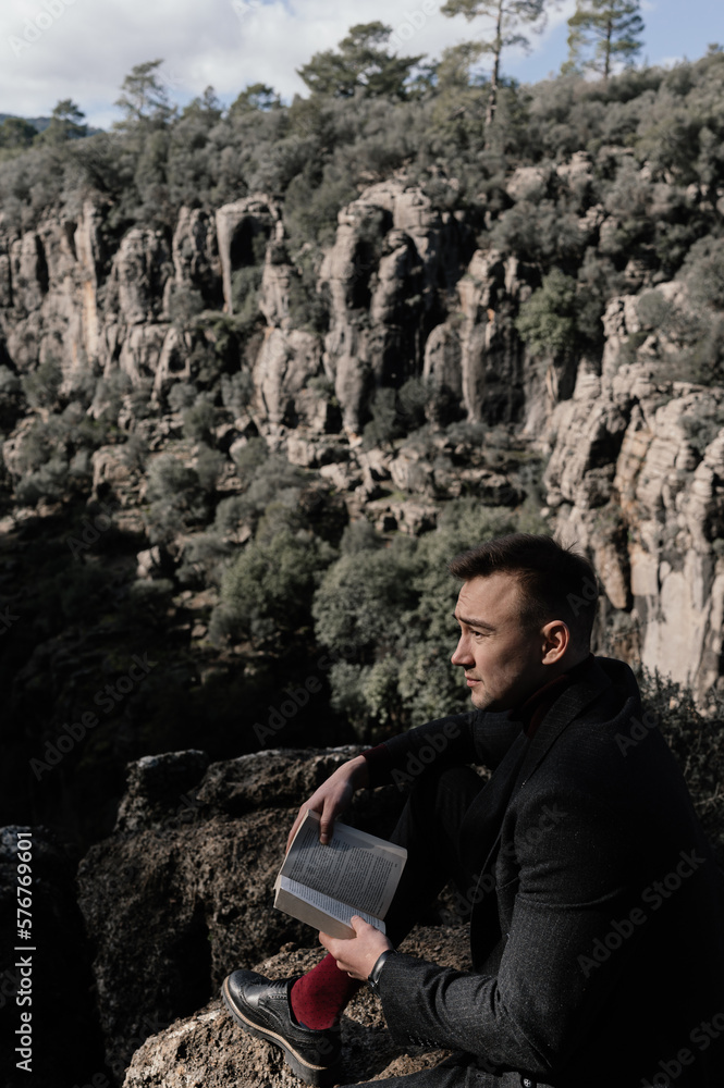 a man in a suit with book on a background of rocks a man in a suit with book on a background of rocks
