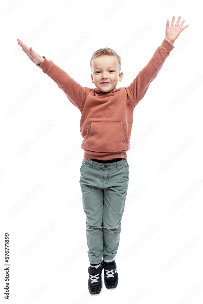 The joyful boy raised his hands up. A blond guy in a brown hoodie and gray trousers. Positivity and happiness. Isolated on white background. Vertical. The joyful boy raised his hands up. A blond guy in a brown hoodie and gray trousers. Positivity and happiness. Isolated on white background. Vertical.