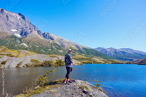 mature man hiker contemplating the beauty of mountains and lake in Torres del Paine National Park Chile © oscargutzo