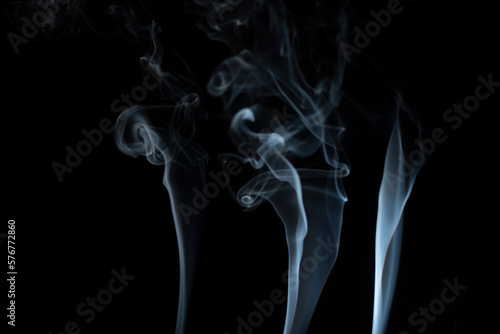 incense stick with light blue smoke against black background