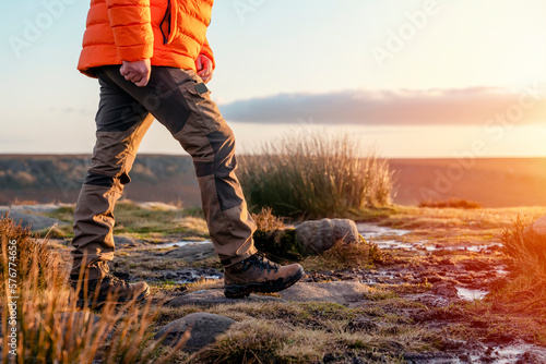 man in speshial boots walking in the mountains reaching the destination and on the top of mountain in Peak District at sunset on autumn day Travel  Lifestyle concept photo