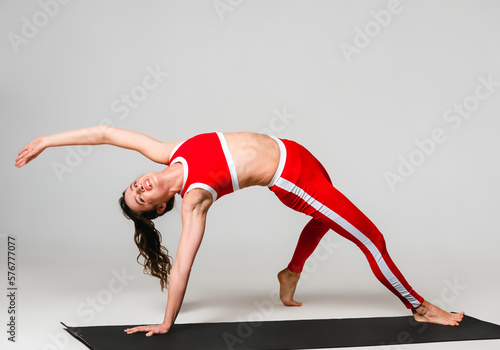 A beautiful woman is exercising in a yoga class for weight loss in the red sportwear