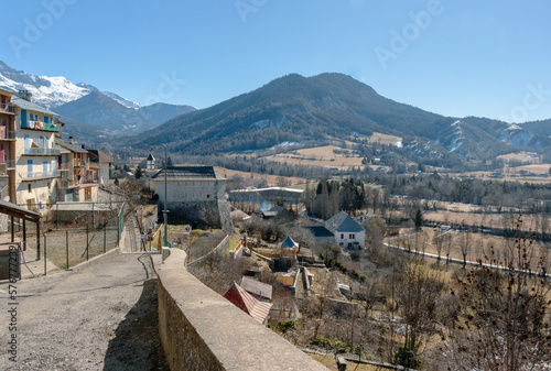 Narrow street in the city of Seyne (also called Seyne-les Alpes), with the Alps mountains covered with snow in the background. photo