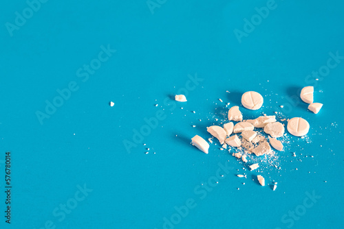 White whole and crushed pills on a blue background. . Concept of medicine. Close-up