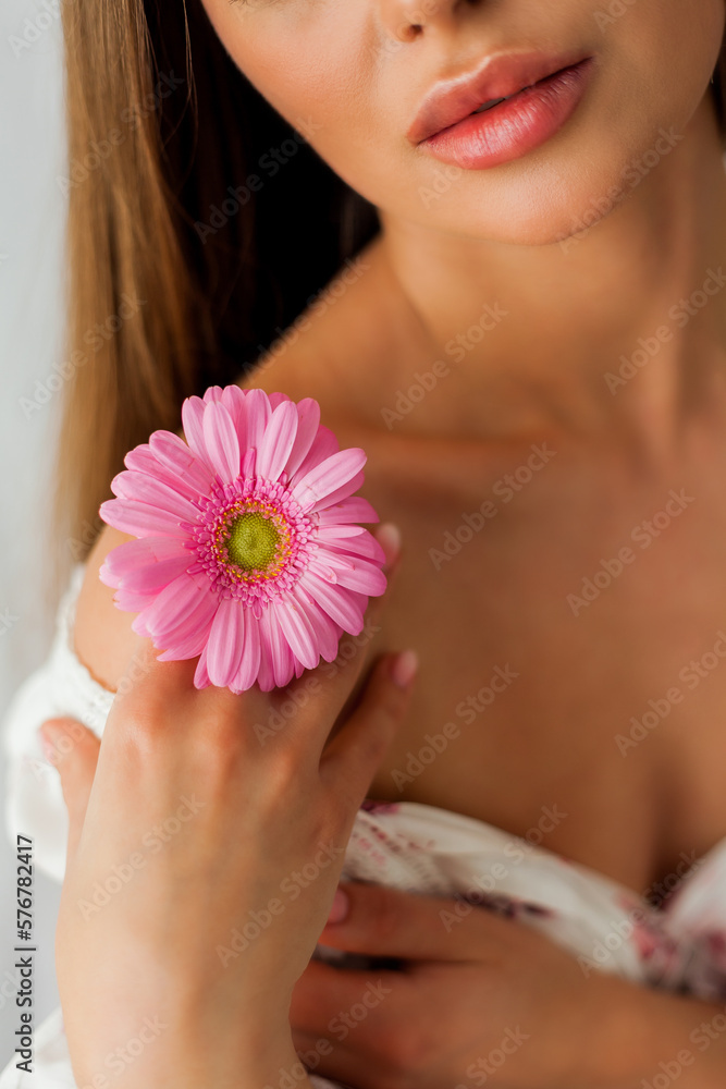 Portrait of young beautiful long-haired brown-eyed woman with pink gerbera on white background. Spring. Holidays. Mothers Day. Portrait of young beautiful long-haired brown-eyed woman with pink gerbera on white background. Spring. Holidays. Mothers Day.
