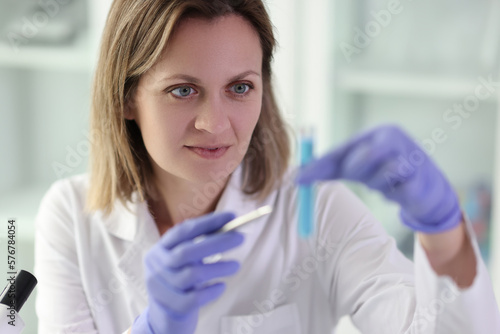 Woman chemist looking at test tube with blue liquid in laboratory