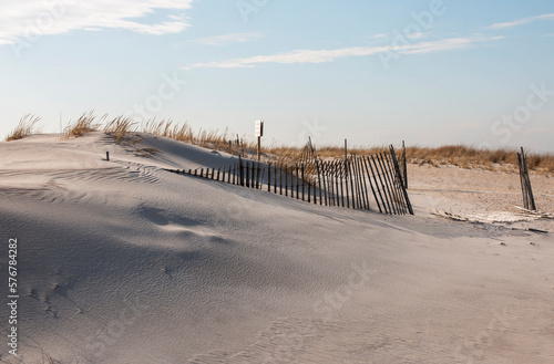 Sand dune with smooth sand blown from the wind buring a wooden fence