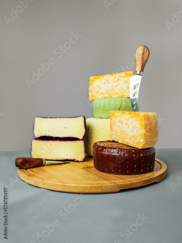 hard and semi-hard cheeses on a wooden cutting board and a cheese knife on a gray background, caciotta ,marble cheese, mint cheese, belper knolle, caciotta in wine, head of cheese photo