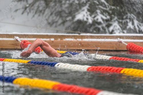 A man swimming in a lake in winter while snow is falling, ice swimming