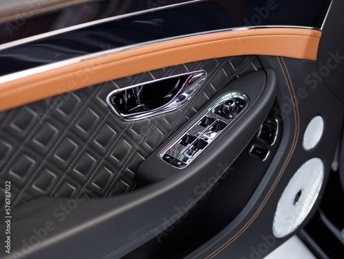 Close-up of the door of a premium car with leather trim and electric seat adjustment, power windows.