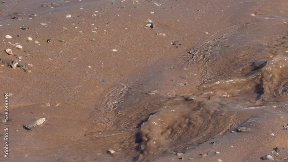wave drops on the beach, detail of sea water running over brown sand wave drops on the beach, detail of sea water running over brown sand