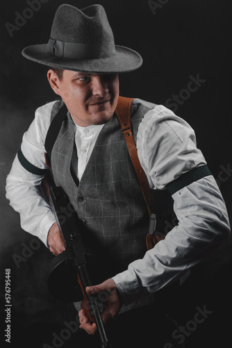 American gangster from Chicago. Early 20th century. Hat and formal suit of shirt and vest. Armed with a pistol and a Thompson submachine gun. A dangerous man who solves problems by force.