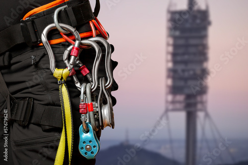 High-altitude equipment, carabiners, block rollers, on a man's belt. Telecommunications, work at height, industrial mountaineering, height, insurance. Close-up. Cell tower.