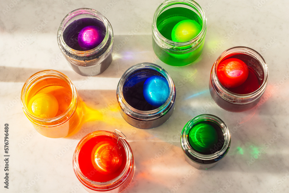 Dyeing Easter Eggs in Colorful Dye in Glass Jars on Marble Counter
