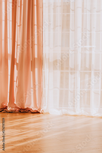 curtains and tulle hang on the window through which the sun's rays penetrate 