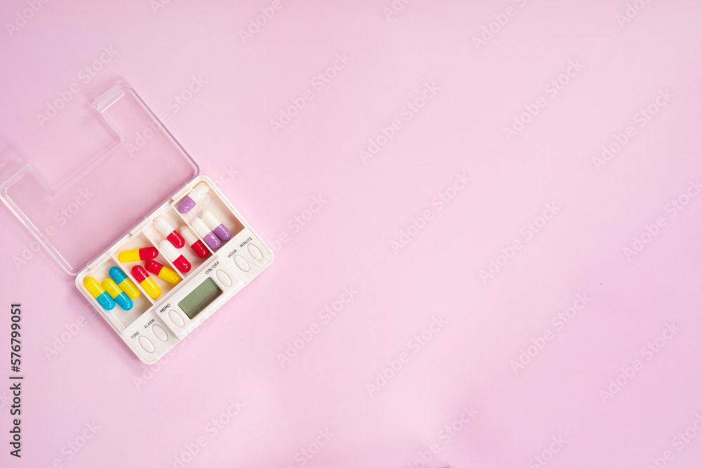 Pill box daily take a medicine, with colorful of pills, tablets, and capsules. Drugs use for treatment and cure the disease on pink background. Medicine concept. Pill box daily take a medicine, with colorful of pills, tablets, and capsules. Drugs use for treatment and cure the disease on pink background. Medicine concept.