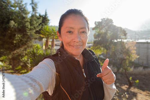 Adult woman smiling at the camera with thumb up while taking a Selfie - Hispanic woman taking a picture with her cell phone - Latin woman enjoying the sunset