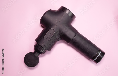 Machine for body massage on pink background. Massage gun. 