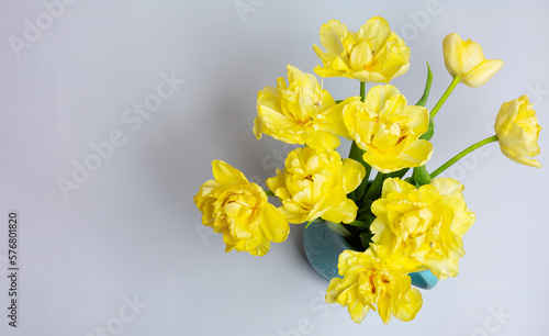 Fototapeta Naklejka Na Ścianę i Meble -  Bouquet fresh yellow tulips in blue ceramic jug on grey-blue background. Top view. Bright spring bouquet for home decor. Concept: birthday, women's day, greeting card. Copy space. Close-up.