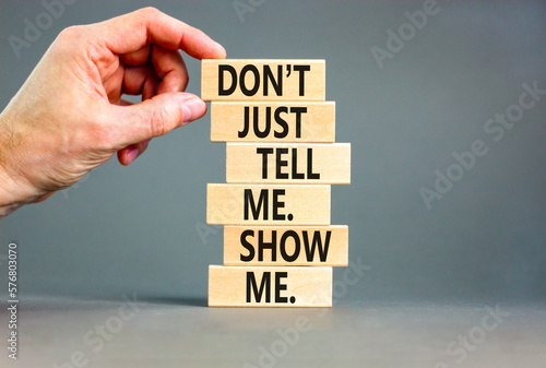 Tell or show symbol. Concept words Do not just tell me, show me on wooden blocks. Beautiful grey table grey background. Businessman hand. Business tell or show concept. Copy space. photo