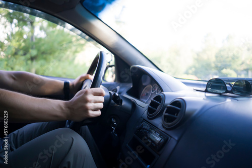 A man is driving a car, hands on the steering wheel closeup.