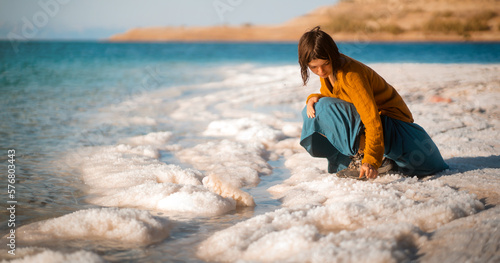 Girl is travelling  sitting on the shore og the Dead Sea.