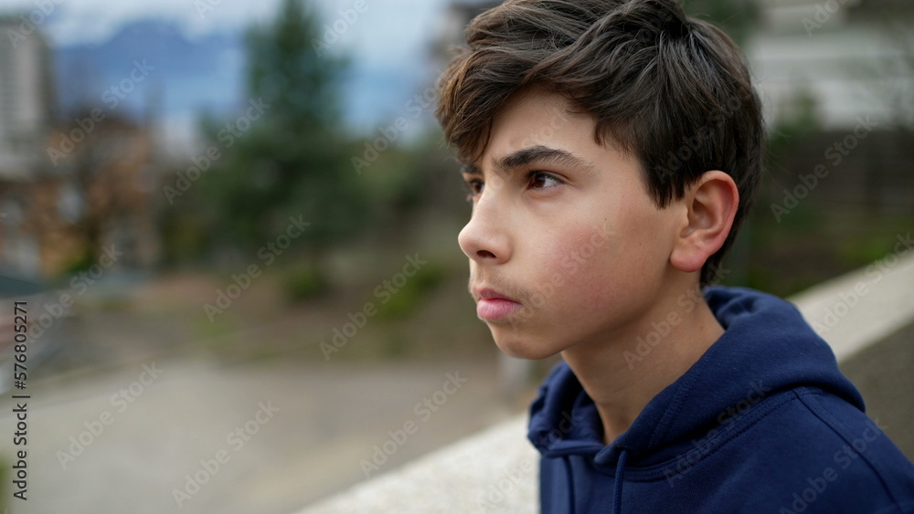 Teen kid stands at park outside staring at horizon in meditation. Tracking shot of young boy in contemplation Teen kid stands at park outside staring at horizon in meditation. Tracking shot of young boy in contemplation