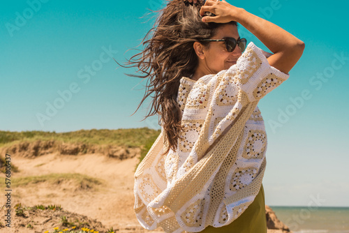 woman on the beach wearing a crochet cardigan made with granny squares, crochet outfit.Outfit spring summer
