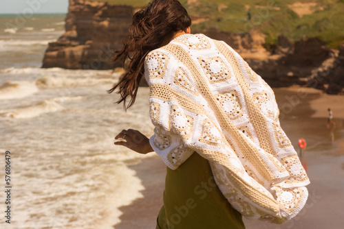 woman on the beach wearing a crochet cardigan made with granny squares, crochet outfit.Outfit spring summer