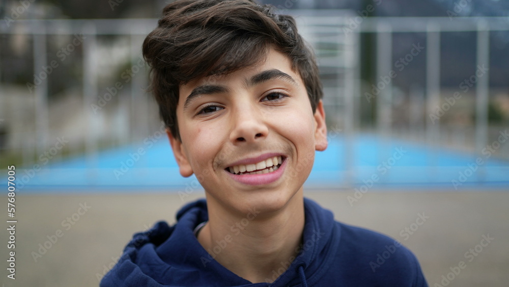 Portrait of a happy young boy smiling at camera. Closeup teenager male kid stands outdoors laughing Portrait of a happy young boy smiling at camera. Closeup teenager male kid stands outdoors laughing