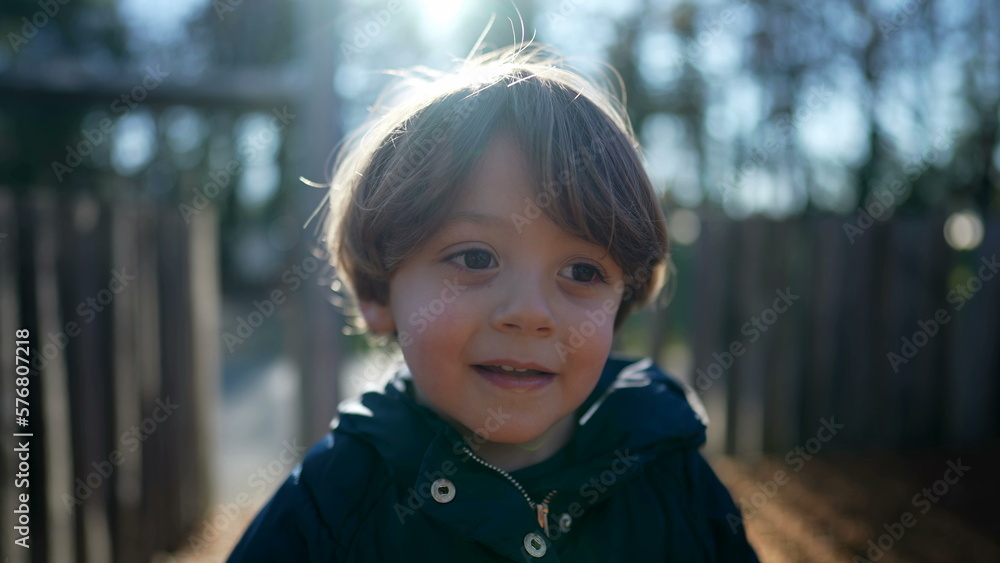 Portrait of a handsome toddler child smiling at camera standing outside during sunny autumn season. Closeup face of little boy in sunlight Portrait of a handsome toddler child smiling at camera standing outside during sunny autumn season. Closeup face of little boy in sunlight