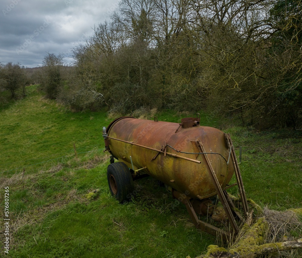 old rusty farm tanker in the corner of a field old rusty farm tanker in the corner of a field