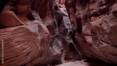 Moving forward along narrow deep slot canyon with smooth red sandstone rocks. Wavy walls of mysterious cave formed by erosion and precipitation. Antelope Canyon is popular place for photos and travel