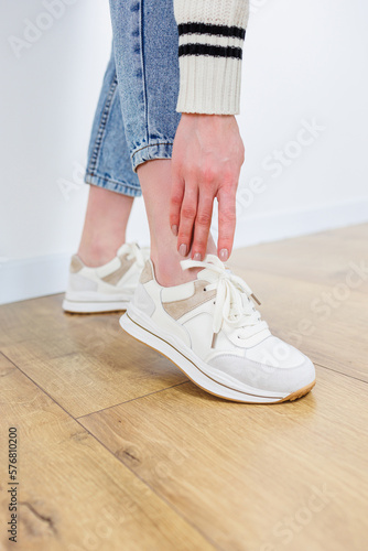 Close-up of female legs in jeans and casual sneakers. Women's comfortable casual shoes. White leather women's sneakers