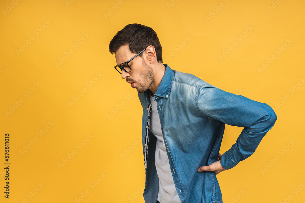 Young handsome man wearing casual standing over isolated yellow background. Suffering of backache, touching back with hand, muscular pain. Young handsome man wearing casual standing over isolated yellow background. Suffering of backache, touching back with hand, muscular pain.
