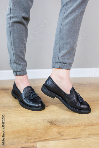 Close-up of female legs in pants and black leather classic shoes. Women's comfortable summer shoes. New spring-summer collection of women's leather shoes 2023