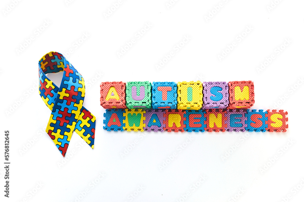 Word Autism Awareness day. Autism Awareness Ribbon and Puzzle cubes on blue background.