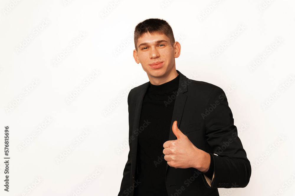 Handsome young smiling man wearing black jacket is holding a thumb up. Handsome young smiling man wearing black jacket is holding a thumb up.