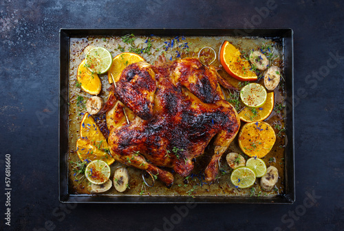 Traditional barbecue spatchcocked chicken al mattone chili with orange, lime and banana slices served as top view on an old rustic metal tray