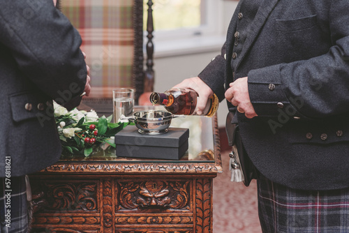 Two men close up pouring whisky into a quaich