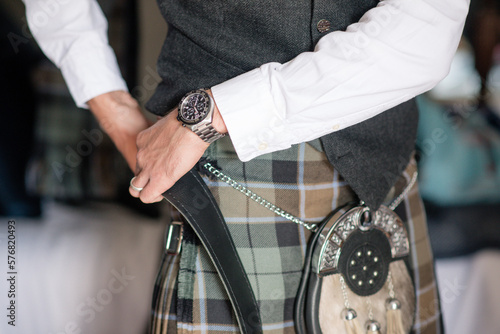 man or groom fastening his kilt belt close up photo