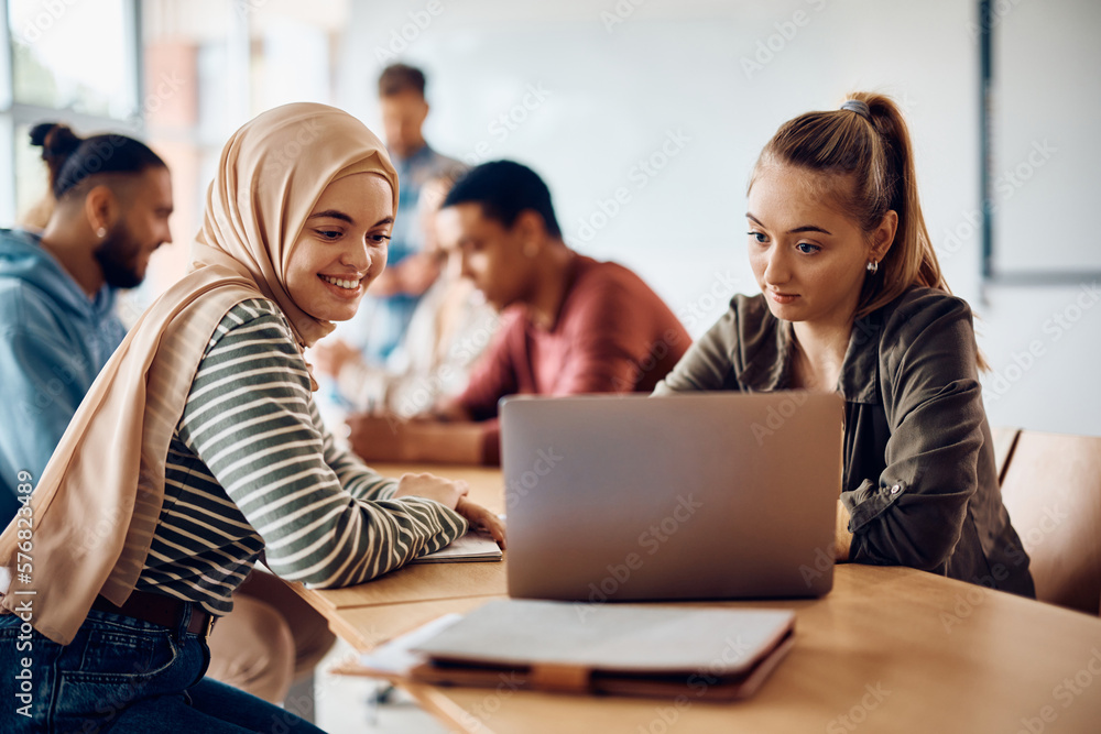 Happy female students using laptop during computer class at university. Happy female students using laptop during computer class at university.