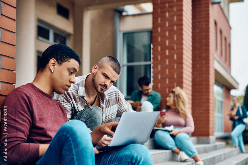 Male college students surfing the net on laptop at campus. Male college students surfing the net on laptop at campus.