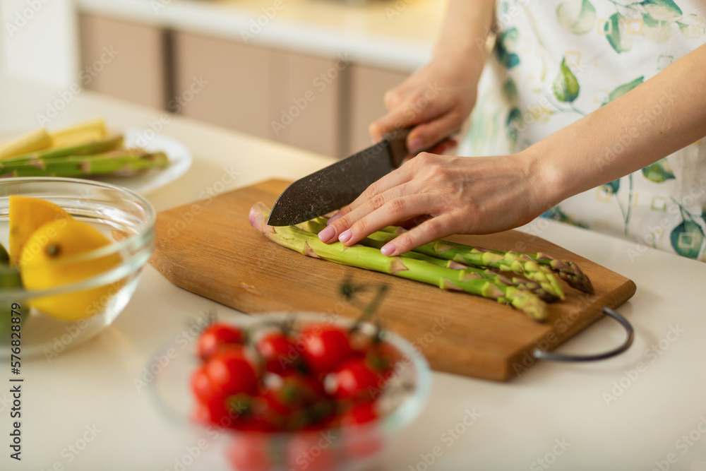 Woman cutting fresh asparagus at table