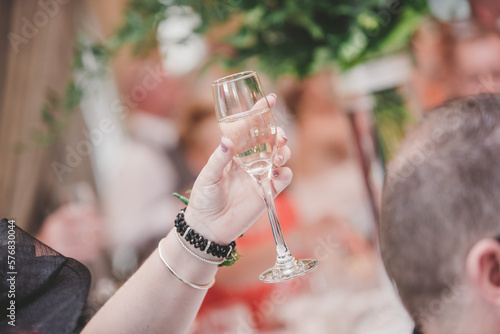 Woman's hand holding glass of champagne or wine making a toast
