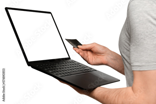 A man in a T-shirt holds a laptop, an ultrabook and a bank card with his second hand, makes an online purchase. photo