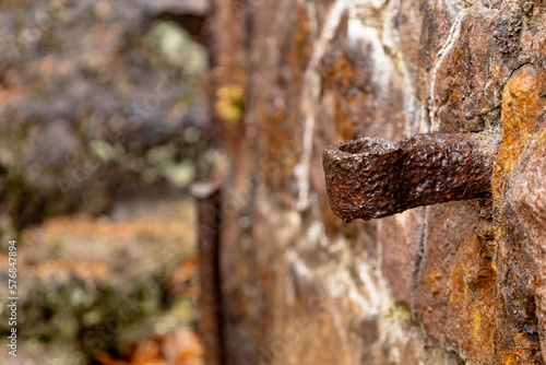 Old rusted iron work piece protruding from stone wall