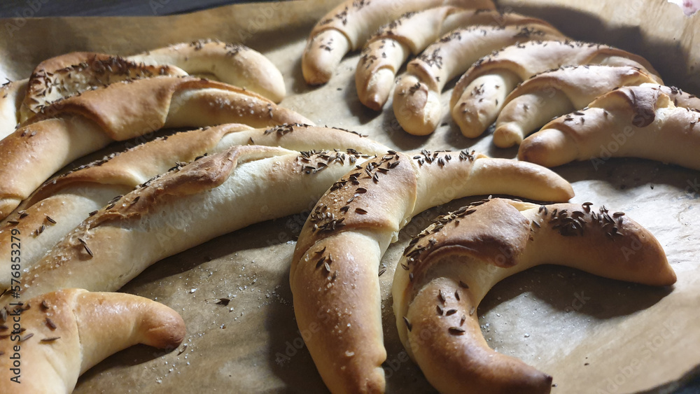 home-baked rolls with cumin and salt on a baking tray with paper