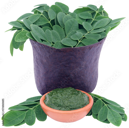 Edible moringa leaves in a vintage mortar with ground paste photo