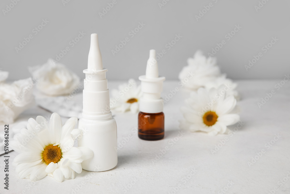 Nasal drops with pills, flowers and tissues on table near grey wall. Seasonal allergy concept Nasal drops with pills, flowers and tissues on table near grey wall. Seasonal allergy concept